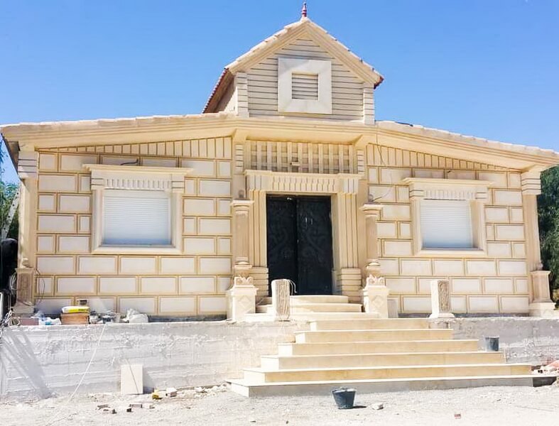 Exterior view of a stone bungalow with garden